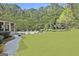 Expansive backyard with lush green lawn, mature trees, and a sparkling swimming pool with poolside seating at 310 Westbourne Dr, Tyrone, GA 30290