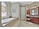 Bright bathroom features a soaking tub, vanity with granite counters and cherry cabinets, and a window for natural light at 310 Westbourne Dr, Tyrone, GA 30290