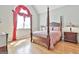 Bright bedroom featuring hardwood floors, a four-poster bed, and a large arched window with red draperies at 310 Westbourne Dr, Tyrone, GA 30290