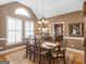 Elegant dining room with large windows, chandelier, and hardwood floors and adjacent kitchen at 1466 Lake Forest Ln, Mcdonough, GA 30253