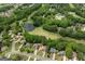 Aerial view featuring homes nestled among lush greenery, with a golf course and pond visible in the distance at 7020 Grand View Way, Suwanee, GA 30024