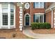 Close-up of a classic brick home showcasing a decorative bay window and arched front door with green shutters at 7020 Grand View Way, Suwanee, GA 30024