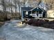 View of the front exterior, featuring a long driveway, front porch, and yard with mature trees at 177 Villa Rosa Way, Temple, GA 30179