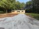 A single-story home features fresh gravel driveway, tan siding, and black shutters at 30 Alyssa Ln, Bowdon, GA 30108