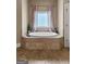 Bright bathroom featuring a tiled, elevated soaking tub and large window at 770 Tralee Dr, Fayetteville, GA 30215