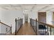 Hallway with decorative railing, hardwood floors, and coffered ceilings, leading to a stone fireplace feature wall at 770 Tralee Dr, Fayetteville, GA 30215