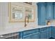 Bright kitchen features custom blue cabinets, a white countertop, and a modern faucet with a large window at 770 Tralee Dr, Fayetteville, GA 30215