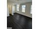 Bright bedroom with three windows, modern light fixture, and dark wood-look floors at 136 Paulownia Cir, Mcdonough, GA 30253