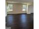 Large living room with two windows and hardwood floors at 136 Paulownia Cir, Mcdonough, GA 30253