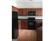 Functional kitchen with wooden cabinets, black appliances, and modern lighting, perfect for everyday meals at 2320 Coach Way, Jonesboro, GA 30236