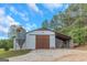 Large white barn with wooden doors, a metal silo, and a tractor parked nearby at 877 Honey Creek Rd, Mcdonough, GA 30252