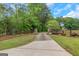 Long driveway to property lined with green foliage and mature trees against a blue sky at 877 Honey Creek Rd, Mcdonough, GA 30252