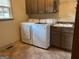 Well-lit laundry room featuring a laundry sink, cabinets and modern washer dryer units at 232 Darwish Dr, Mcdonough, GA 30252