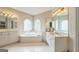 Bright bathroom featuring a soaking tub beneath arched windows and dual vanities with a tile floor at 2693 Blairsden Nw Pl, Kennesaw, GA 30144