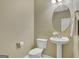 Cozy half-bathroom features decorative mirror, pedestal sink, and white toilet at 340 Aster Ridge Trl, Peachtree City, GA 30269