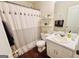 Bright bathroom featuring dark wood floor, shower-tub with decorative curtain, vanity with sink, and wall shelving at 1741 Portwest Way, Hampton, GA 30228
