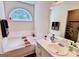 Bright bathroom featuring a soaking tub under an arched window and double vanity at 1741 Portwest Way, Hampton, GA 30228