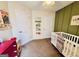 A bedroom with green accent wall, white crib, and other decorations at 1741 Portwest Way, Hampton, GA 30228