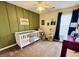 A bedroom with green accent wall, white crib, and other decorations at 1741 Portwest Way, Hampton, GA 30228