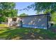 Home's backyard with a small, covered back porch, chain link fence, and mature shade trees at 50 Caroline Ave, Stockbridge, GA 30281