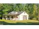 Charming white barn-style house with a metal roof nestled among mature trees on a sunny day at 155 Green Meadow Ln, Fayetteville, GA 30215