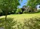 Expansive backyard with lush green grass, mature trees, and a view of the brick home at 1345 Cashiers Way, Roswell, GA 30075