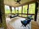 A beautiful screened-in porch with a porch swing, blue chairs, wood flooring, and natural outdoor views at 1345 Cashiers Way, Roswell, GA 30075