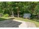 Backyard featuring mature trees, storage shed, and a concrete patio, creating a serene outdoor space at 135 Gingercake Ct, Fayetteville, GA 30214