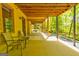 Covered patio with seating, offering shade and a tranquil view of the surrounding trees at 8575 Haven Wood Trl, Roswell, GA 30076