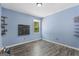 A blue bedroom with light wood flooring, shelves, and a window at 6942 Cottonwood Trl, Riverdale, GA 30296