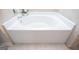 Close-up of a clean, bright white bathtub with chrome fixtures and neutral-toned tiled surround at 137 River Birch Dr, Carrollton, GA 30116