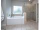 Bright bathroom features a soaking tub, a glass enclosed shower, and neutral tile flooring at 137 River Birch Dr, Carrollton, GA 30116