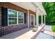 Cozy covered porch with brick detailing, white pillars, and inviting decor, creating a pleasant entrance at 137 River Birch Dr, Carrollton, GA 30116