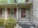 Charming front porch and door of this brick home, framed by lush greenery and red shutters at 780 Sweet Briar Se Trl, Conyers, GA 30094