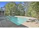 Backyard view of a sparkling swimming pool surrounded by mature trees and a concrete deck at 180 Willow Lake Ln, Sharpsburg, GA 30277