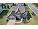 Aerial view of a lovely home featuring a gray brick exterior, dark shutters, and a three-car garage at 7575 Old Camp Lndg, Cumming, GA 30040