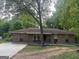 Charming brick home with a classic design, featuring a covered porch, gravel landscaping, and a mature tree in the front yard at 8145 Attleboro Dr, Jonesboro, GA 30238
