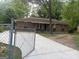 Charming brick home featuring a classic design and an expansive concrete driveway, all enclosed by a secure chain-link fence at 8145 Attleboro Dr, Jonesboro, GA 30238