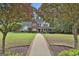 Inviting two-story home featuring a brick pathway, lush greenery, and mature trees at 908 Huntington Pl, Peachtree City, GA 30269