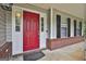 Inviting front porch with a bright red door, black shutters, and well-maintained landscaping at 908 Huntington Pl, Peachtree City, GA 30269