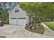 Attached two-car garage with a side yard featuring a bench, landscaping, and a mature tree at 908 Huntington Pl, Peachtree City, GA 30269