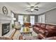 Bright living room featuring a brick fireplace, ceiling fan, hardwood floors, and plush seating at 908 Huntington Pl, Peachtree City, GA 30269
