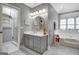 Gray bathroom featuring a soaking tub, glass shower, gray vanity and round mirror at 302 Welton Way, Peachtree City, GA 30269