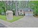 Beige two-story home with an attached two-car garage, nestled within a green wooded neighborhood at 302 Welton Way, Peachtree City, GA 30269