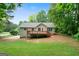 Landscaped backyard with a wooden deck extends from a charming house on a sunny day at 142 Pebblebrook Way, Temple, GA 30179
