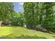 Lush green backyard featuring mature trees, outbuildings, and a wooden play area at 40 Salem Ct, Mcdonough, GA 30252