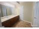 Bathroom with double sink vanity, a large mirror with lighting, and tiled floors at 6190 Winston Trce, Mcdonough, GA 30252