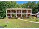Stunning two-story brick home with double balconies, columns, a well-manicured lawn, and a walkway at 871 Rocky Creek Rd, Hampton, GA 30228