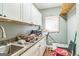 Functional utility room with white cabinetry, sink, and wood-style flooring at 871 Rocky Creek Rd, Hampton, GA 30228
