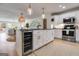 Modern kitchen with white cabinets, stainless steel appliances, granite countertops, island, and pendant lights, adjacent to the living area at 705 Berry Ct, Villa Rica, GA 30180